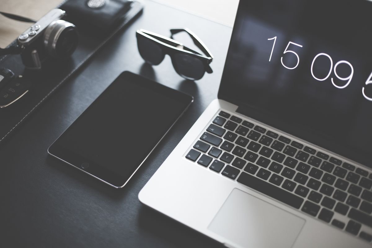Designer desk with a laptop, tablet, camera and sunglasses