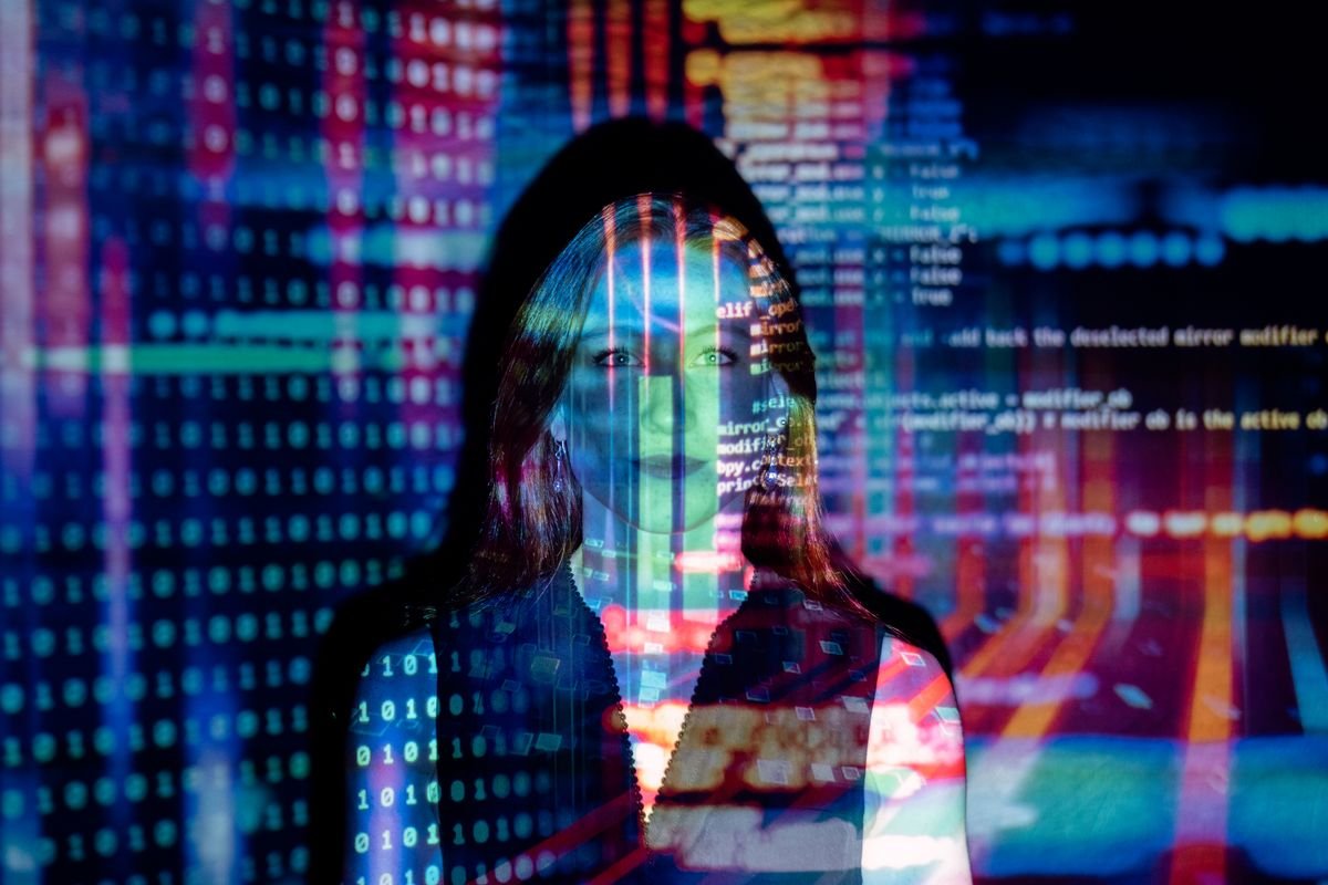 Woman lit by projected lines of code and binary digits